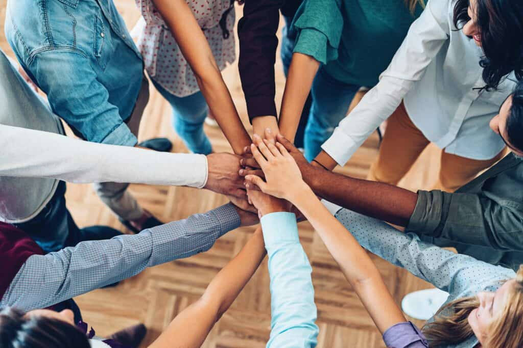 aerial view of a stack of 10 hands ready for a team cheer